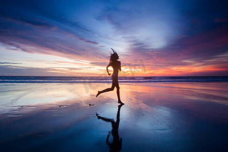 夕阳下在沙滩上奔跑的女人