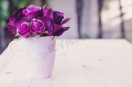 杯子里的紫色人造玫瑰为爱画心。