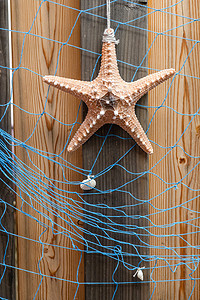 风化木板上带海星和蓝网的海星背景、设计和装饰