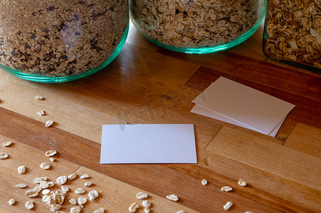 背景名片模板摄影照片_桌子上的名片模型模板，上面撒有燕麦片 — 背景是麦片罐