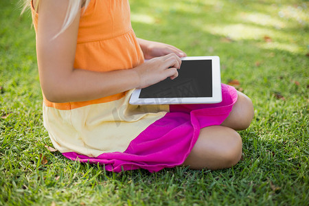 在公园里使用数字平板电脑的年轻女孩