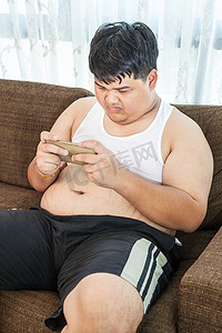 亚洲胖男人用他的智能手机玩游戏