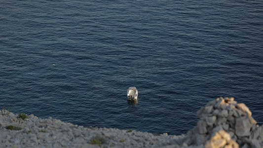 有人的小发射小船，蓝色海，岩石海岸