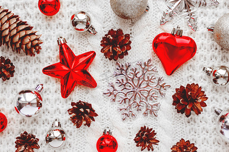 圣诞节和新年背景与装饰-球、星星、银色闪闪发光的雪花、带有装饰图案的针织面料上的心。
