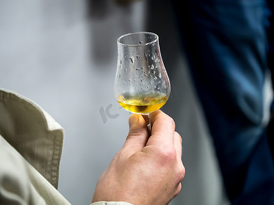 手拿着装满威士忌的小酒杯