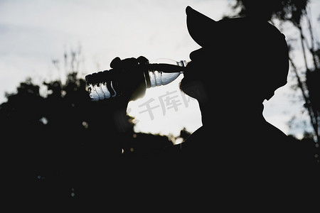 喝水的男人摄影照片_一个男人在运动后从瓶子里喝水的特写。 