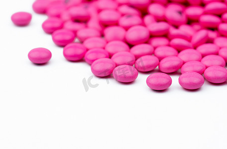 特写一堆粉红色圆形糖衣药丸，在白色背景下与复制空间隔离。