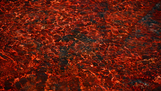 红色水浪摄影照片_红色的流水浪过石头