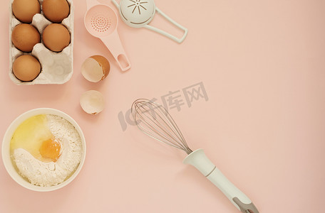 厨房烘焙工具摄影照片_用于烹饪蛋糕或糖果的配料和厨房烘焙工具 — 鸡蛋、面粉、粉红色背景上的拂尘。