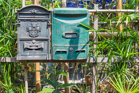 绿色栅栏摄影照片_栅栏上的两个旧邮箱
