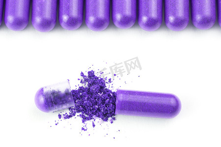 胶囊紫色摄影照片_白色背景上分离的一排质子紫色有机胶囊，特写一个打开