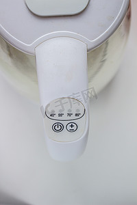 水壶上的按钮摄影照片_电热水壶上的电源和温度按钮是白色的。
