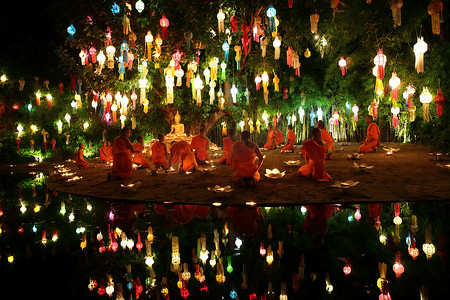 泰国僧侣在许多灯笼中的佛像周围冥想