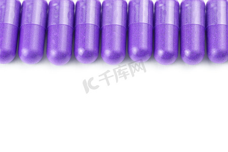 在白色背景上分离的一排质子紫色有机胶囊，特写有选择的焦点
