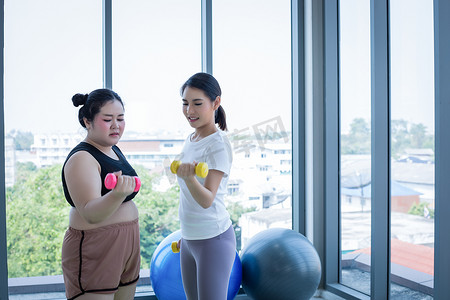 亚洲胖女人和教练在健身课上锻炼，教练建议肥胖女性进行减肥运动