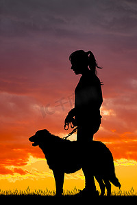 日落时女孩和狗的剪影