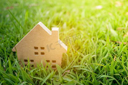真实的绿色小草摄影照片_关闭在绿草的微小的家庭模型有阳光背景。