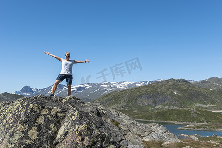 观光地摄影照片_成年女性在岩石上快乐地看着蓝色的水