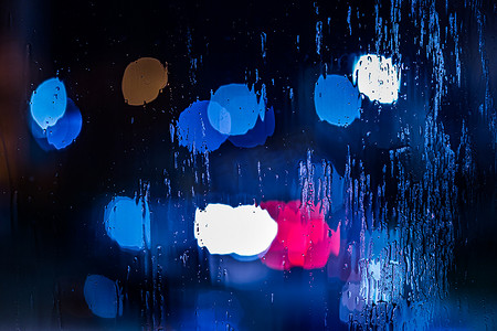 警灯gif摄影照片_红色和蓝色警灯的抽象背景在夜间通过湿玻璃特写，有选择地聚焦