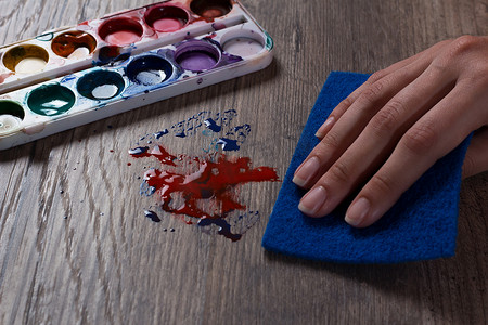 一只手用蓝色海绵擦拭油漆上的污渍。woma