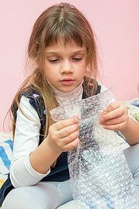 五岁女孩坐在床上吃泡泡包装