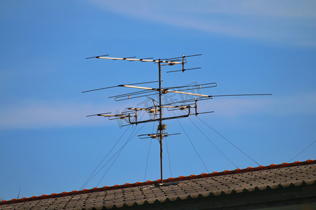信号传输摄影照片_天线、天线电视信号传输、家庭屋顶和天蓝色的低频天线电视农村