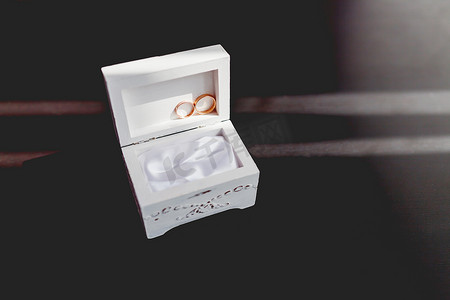 一对金色结婚戒指，白色破旧装饰盒上镶有钻石。