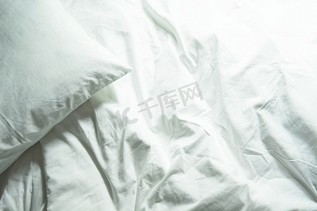 床上的白色枕头和卧室里皱巴巴的凌乱毯子，F