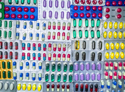 药片图案摄影照片_泡罩包装中五颜六色的药片和胶囊药丸的顶部视图排列着美丽的图案。