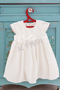 红色衣架上挂着可爱的白色蕾丝连衣裙。