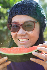 牙齿吃西瓜摄影照片_把吃西瓜的年轻女人的脸特写起来，永远使用