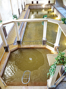 几个室内游泳池，墙壁上有绿水、柱子和装饰性植被