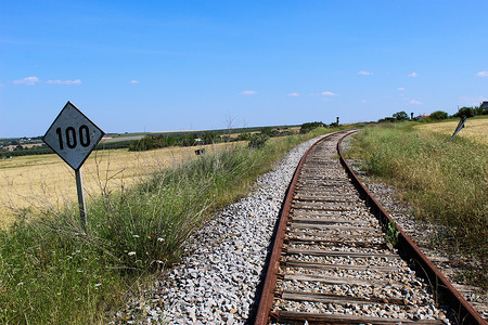 数字100摄影照片_旧铁路旁边有数字一百的旧方形标志。