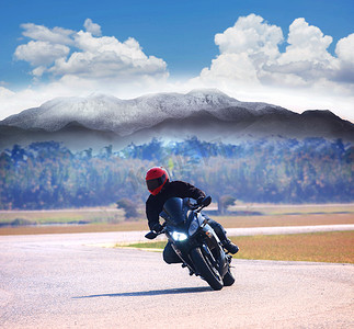 年轻人骑摩托车在柏油路上对抗山高