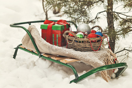 雪橇、毯子、带玩具的篮子和雪地里的礼盒