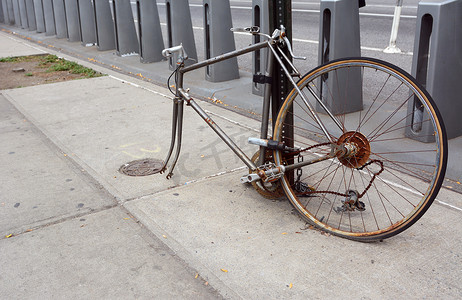 车轮的辐条摄影照片_锁在一根金属杆上的破旧生锈自行车