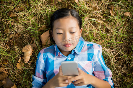 躺在草地上玩手机的女孩