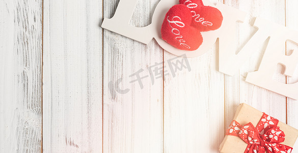 扁平文字框摄影照片_白色木质背景上的爱情文字、礼品盒和心形符号