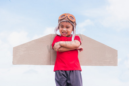小男孩微笑着戴飞行员帽玩玩具飞机机翼