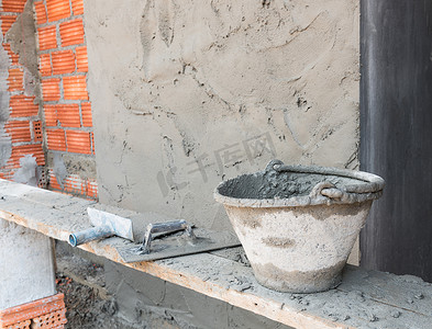 水泥桶摄影照片_红砖墙背景的水泥桶和工具施工