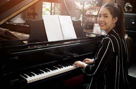 美丽的亚洲女孩学会弹钢琴。