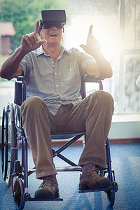 老人沙发摄影照片_坐在轮椅上的快乐老人使用 VR 耳机