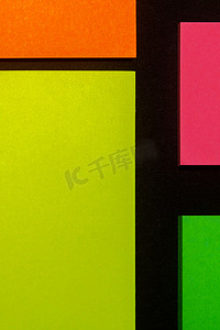黑纸上的绿色、黄色、橙色和玫瑰色彩色办公室贴纸。 