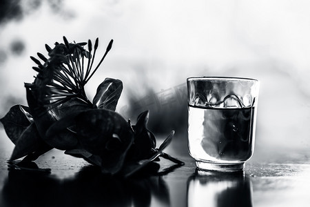 梦幻五角星摄影照片_在透明玻璃碗中关闭木质表面的红色五角花或埃及星花或茉莉花，其提取的水。