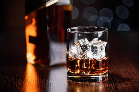 一杯加冰的威士忌和桌上的一瓶。