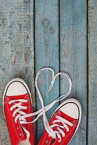 蓝色木质背景上的一双红色复古运动鞋，鞋带
