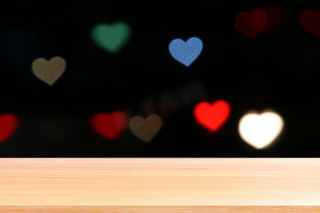 木板在照明五颜六色的心形散景黑色背景上，空木桌地板在心形散景夜光多色背景上，木桌板在散景心形光上空