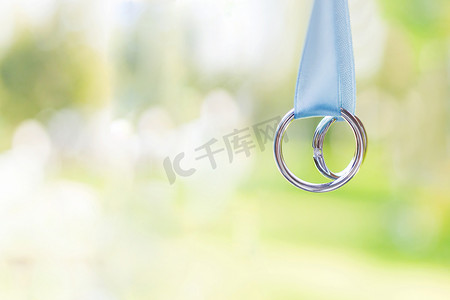 一对金色结婚戒指，浅蓝色丝带上镶有钻石。