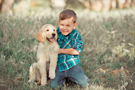 可爱帅气的蓝眼睛男孩在户外玩耍，带着令人惊叹的白色粉红色拉布拉多猎犬小狗，享受夏日阳光明媚的假期周末，充满快乐。快乐的微笑孩子和最好的朋友