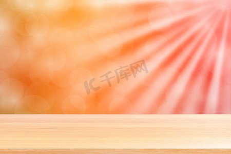 渐变背景绿色摄影照片_空木桌地板在柔和的橙色散景灯光束闪耀渐变背景上，木板空在橙色散景彩色灯光照耀下，彩色散景灯渐变柔和，用于横幅广告